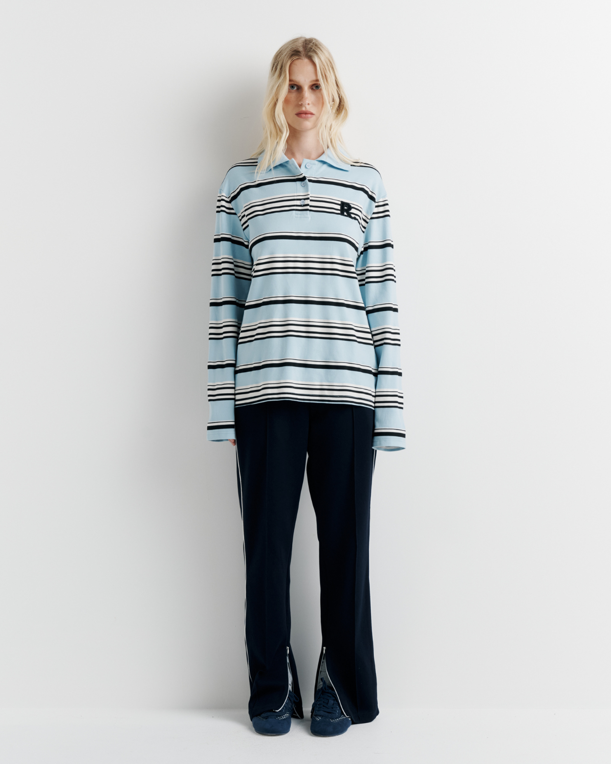Model wearing the Varsity Polo – blue long sleeve polo shirt with classic collar and relaxed fit by ROMY.