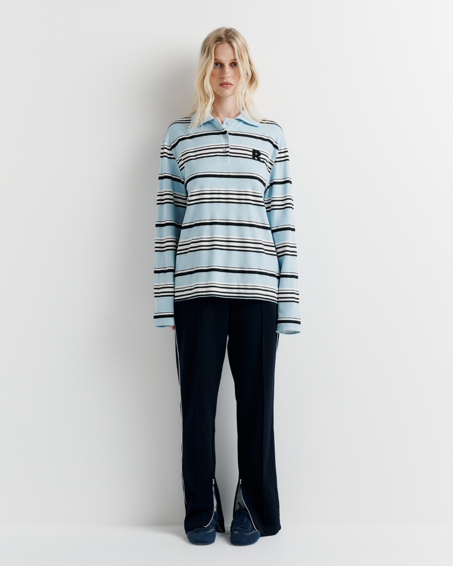 Model wearing the Varsity Polo – blue long sleeve polo shirt with classic collar and relaxed fit by ROMY.