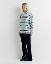 Model wearing the Varsity Polo – blue long sleeve polo shirt with classic collar and relaxed fit by ROMY.