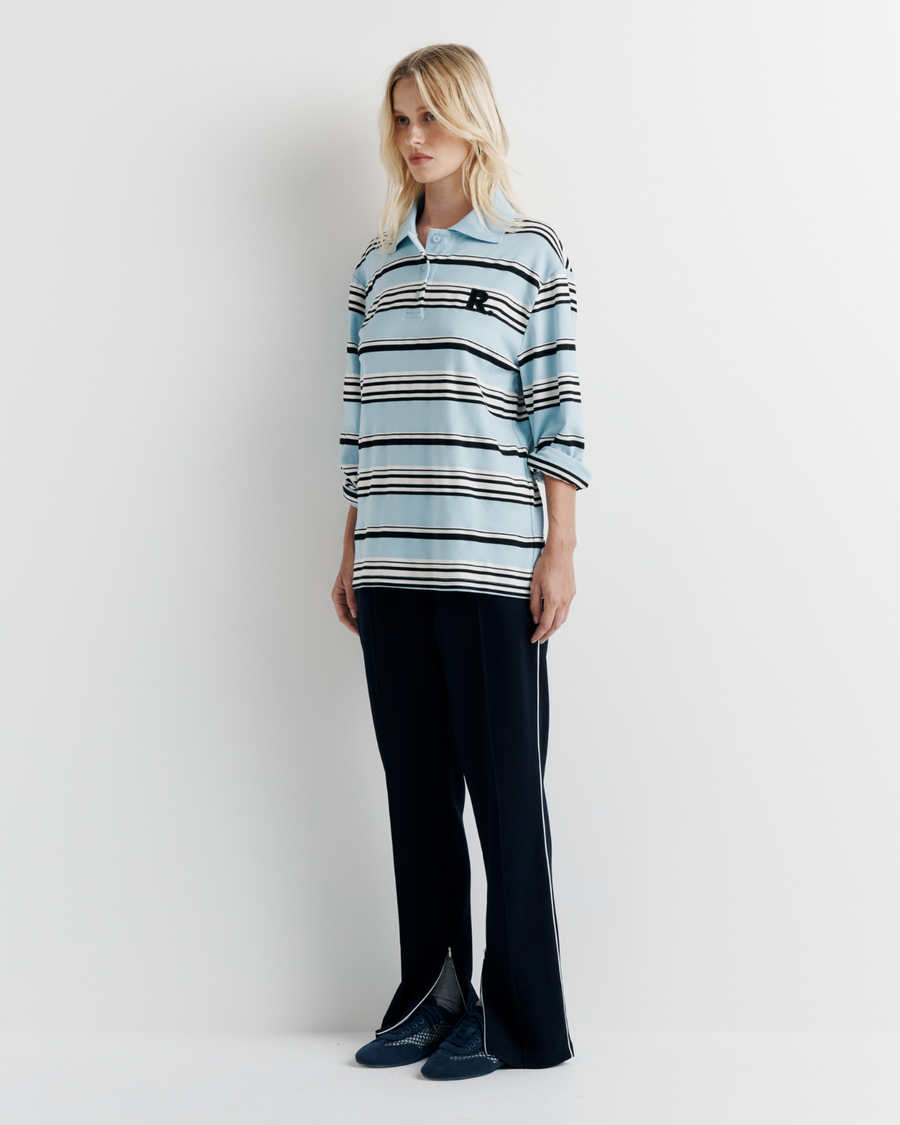 Model wearing the Varsity Polo – blue long sleeve polo shirt with classic collar and relaxed fit by ROMY.