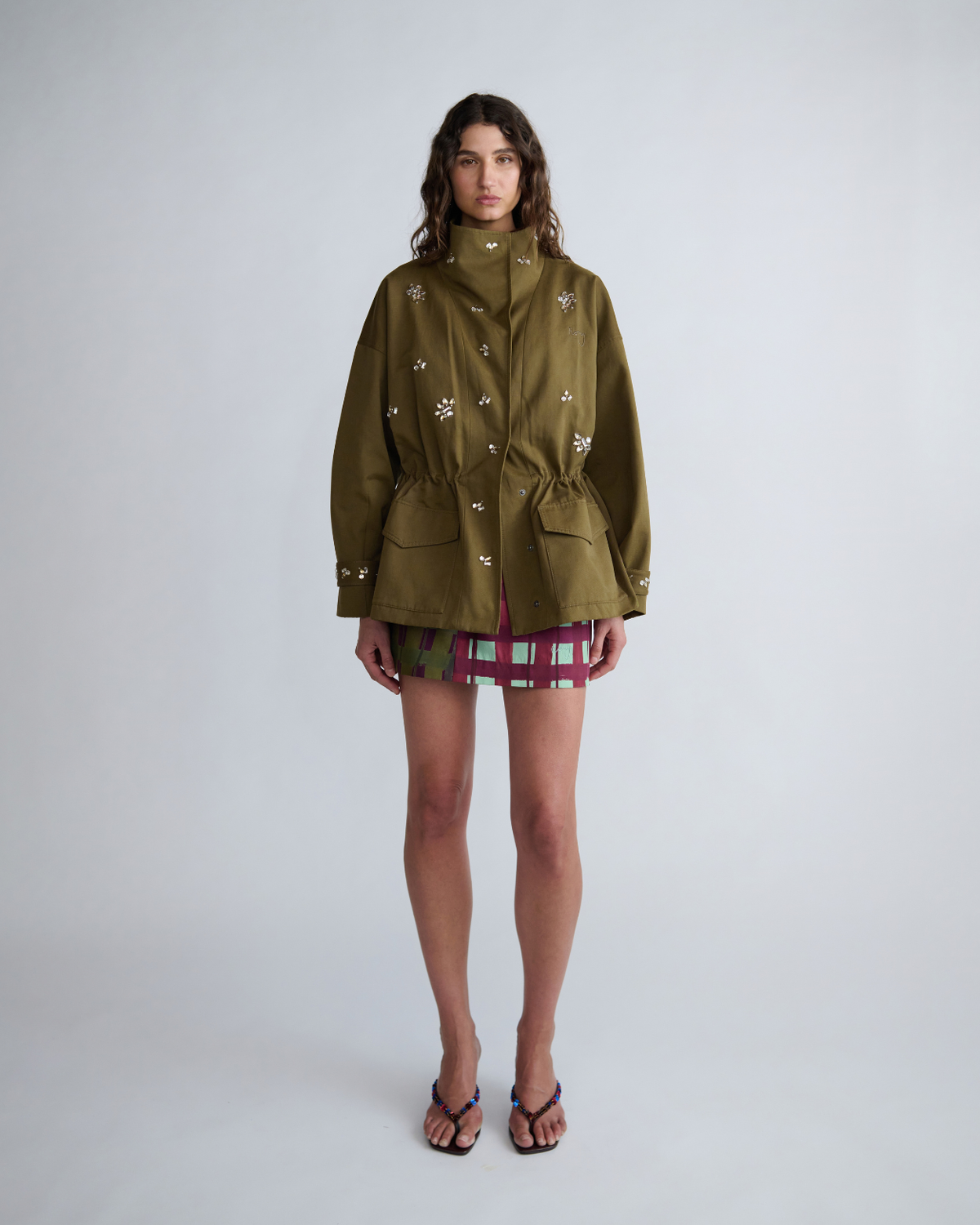 Full-length front view of the khaki Forever Jacket by ROMY styled with a checked mini skirt.