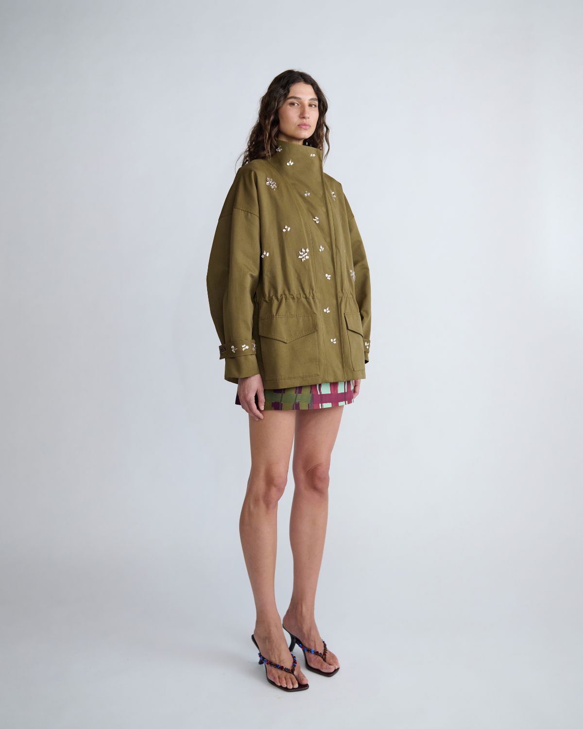 Three-quarter view of the khaki Forever Jacket showing its relaxed utility silhouette and embellished detailing.