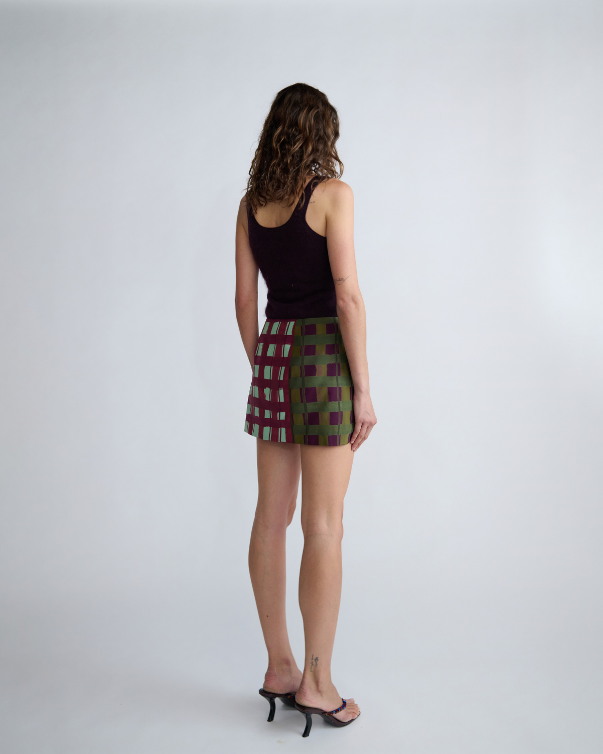 Back view of the ROMY Ardent Skirt featuring a low-rise fit and original burgundy, olive and mint check design.
