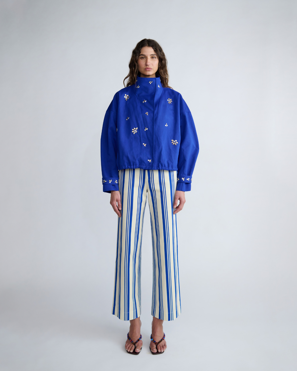 Full-length front view of the ROMY Cropped Forever Jacket styled with striped River Pants and high funnel neckline.