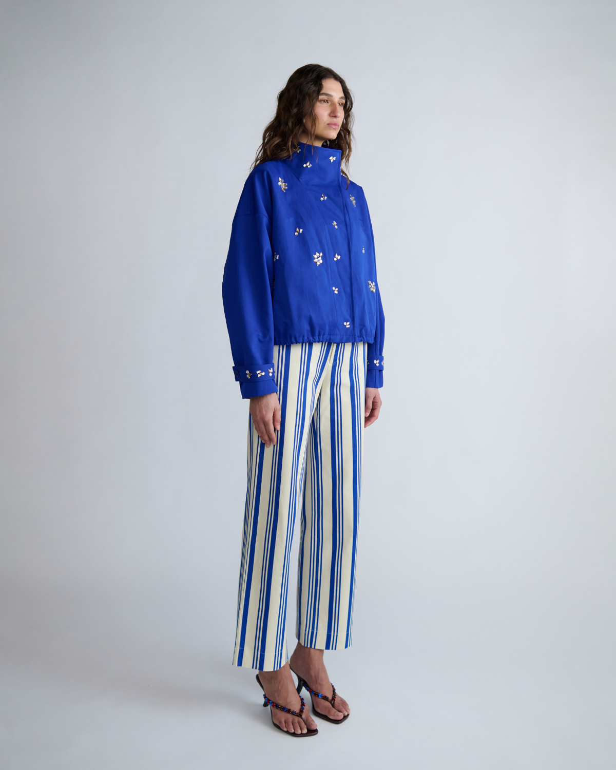 Three-quarter view of the cobalt blue cropped jacket showing its oversized sleeves, embellished front and relaxed silhouette.