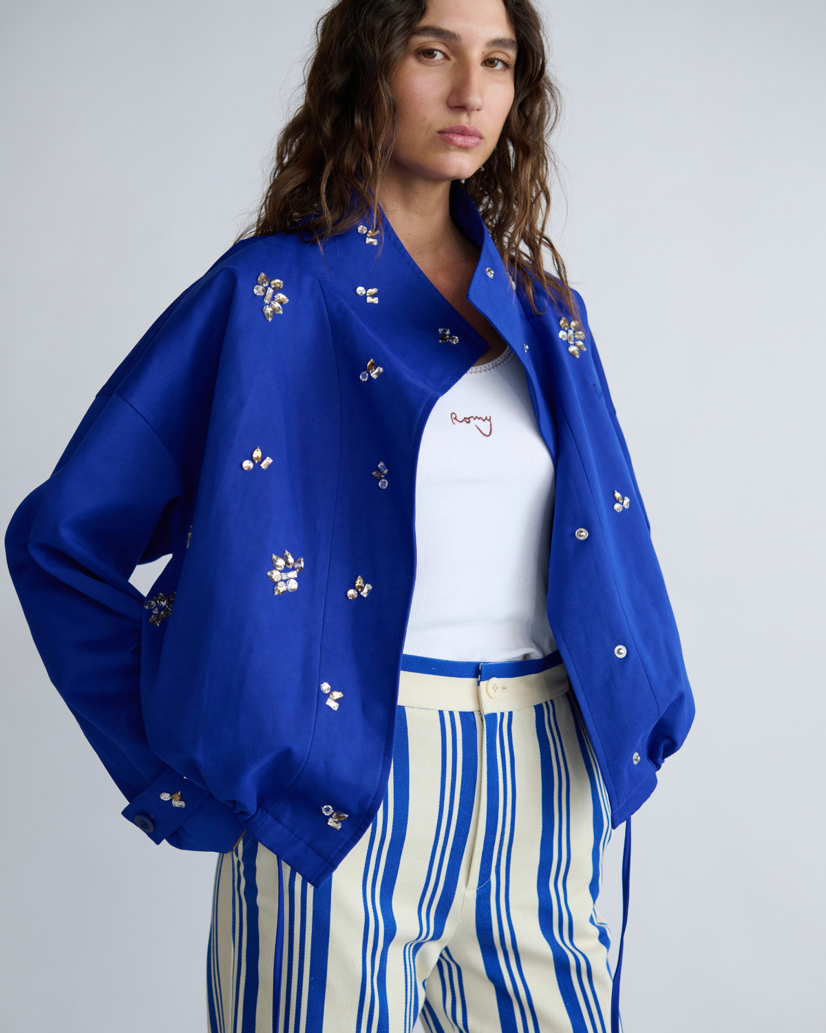 Model wearing the cobalt blue Cropped Forever Jacket open over a white tank and blue striped pants.