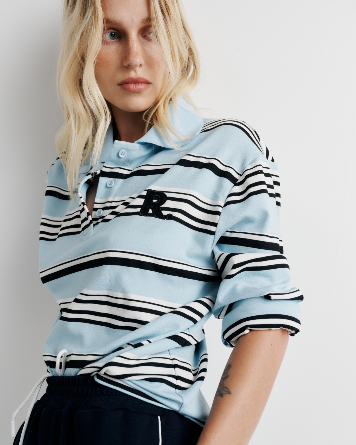 Model wearing the Varsity Polo – blue long sleeve polo shirt with classic collar and relaxed fit by ROMY.