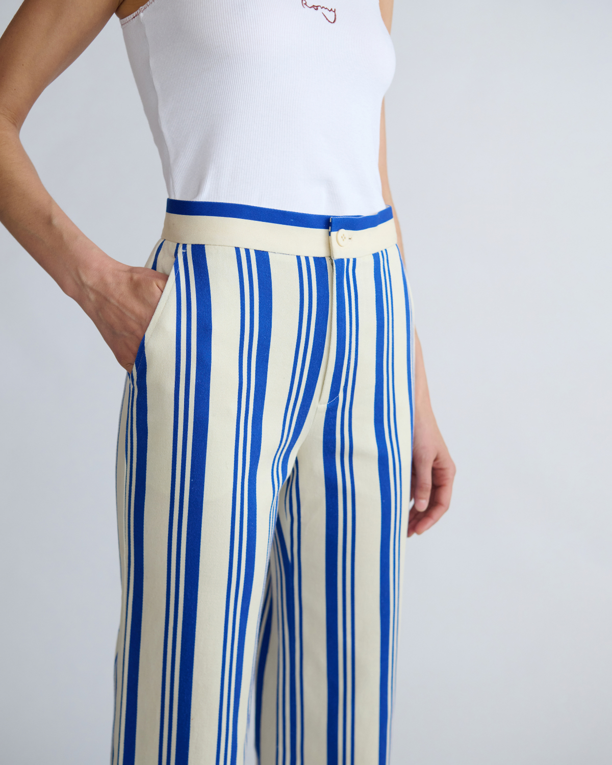 Close-up of ROMY River Pants showing the blue and cream stripe print, mid-rise waistband and side pockets.