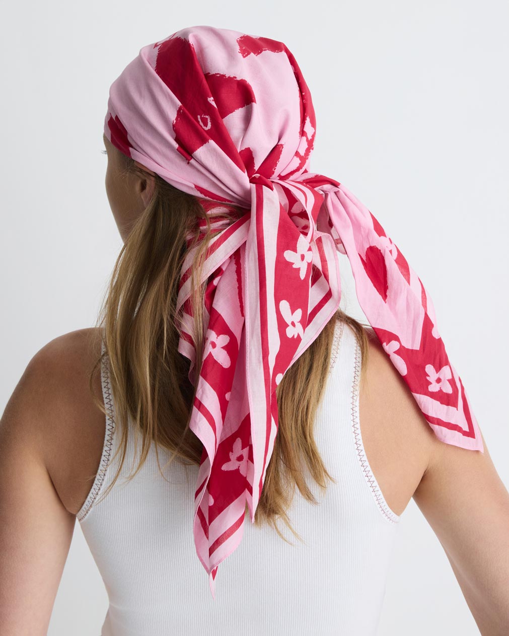 Summer Love Scarf in pink and red print, worn in the hair, back view on model.