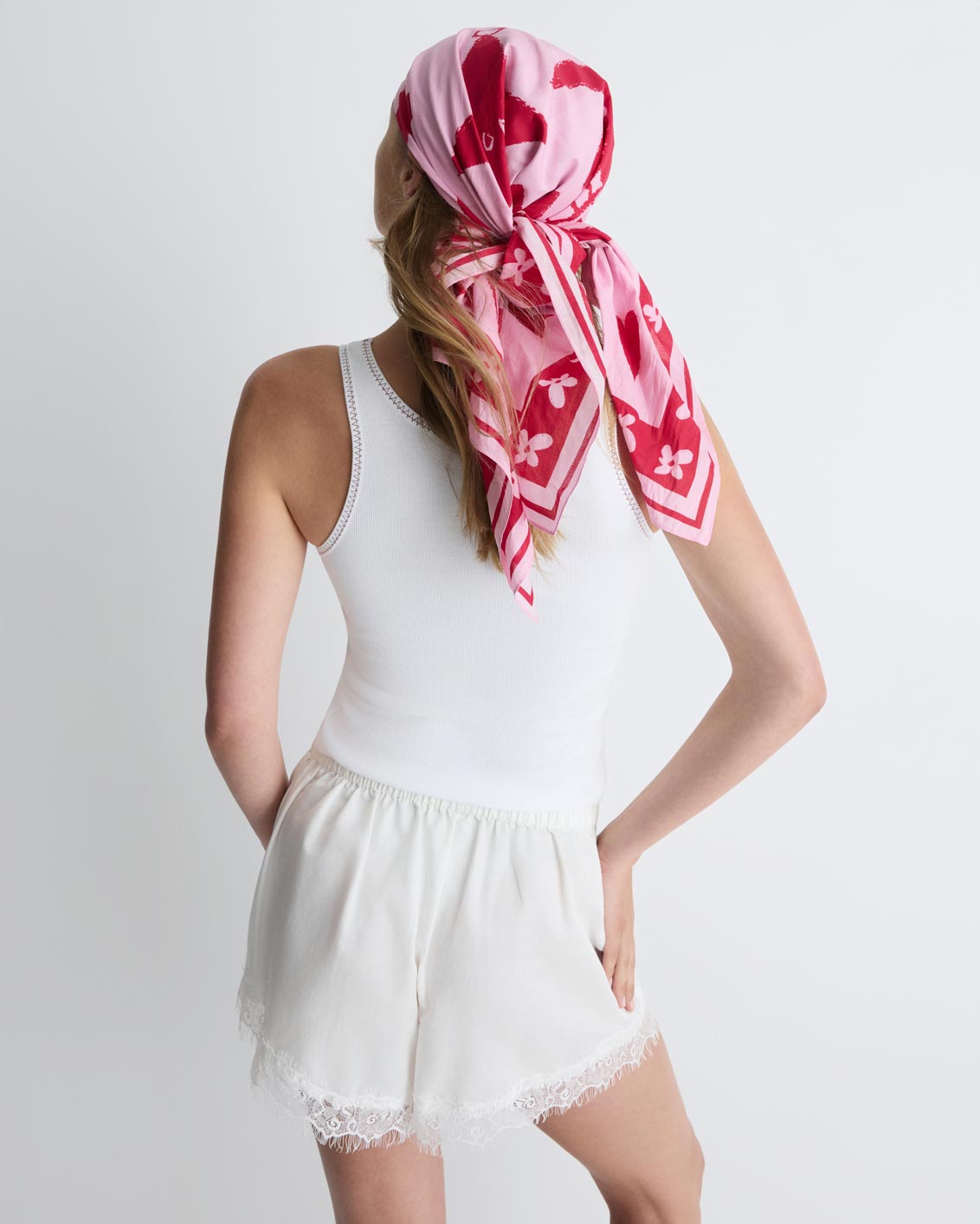 Summer Love Scarf in pink and red print, worn in the hair, back view on model, full.