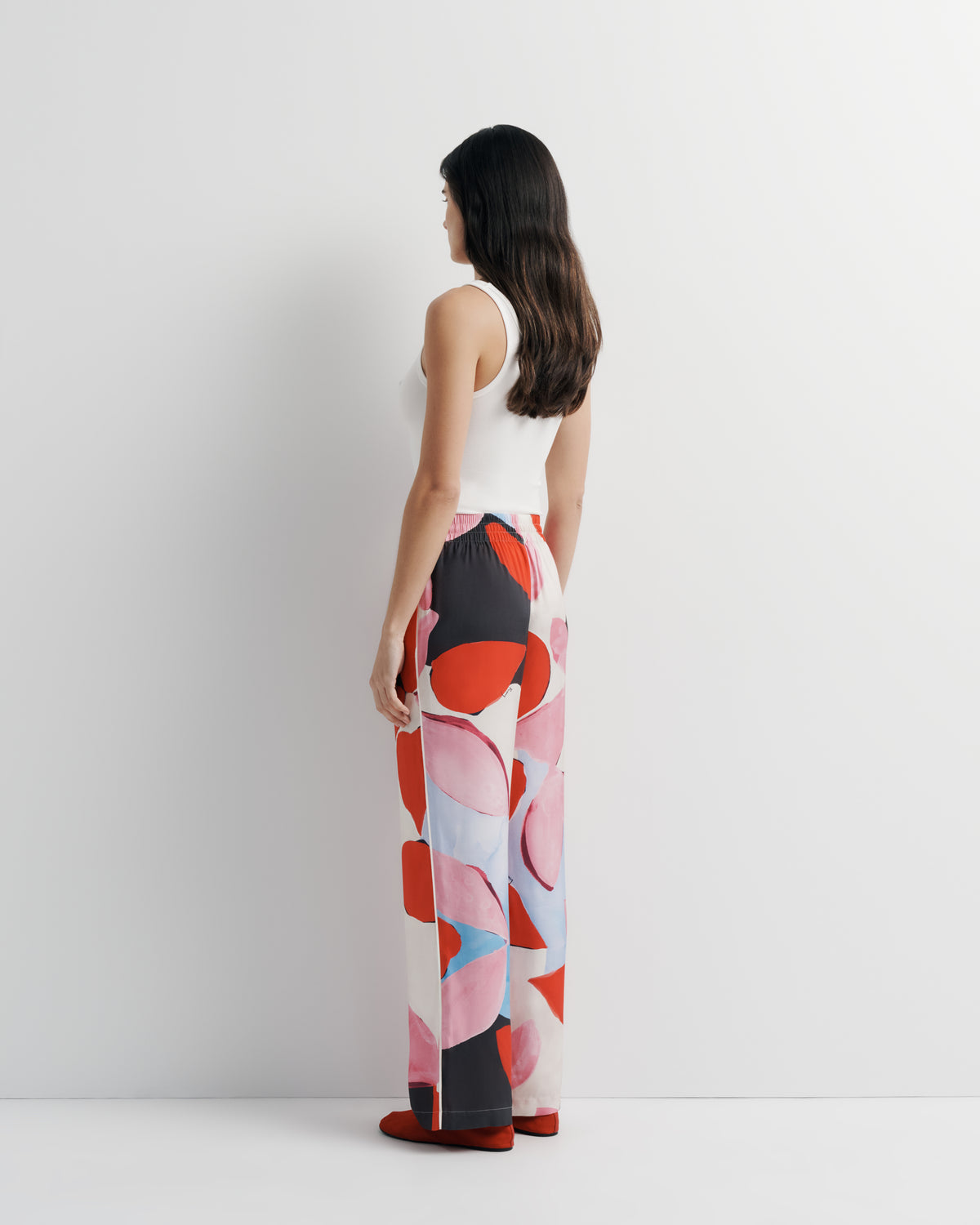 June Pant in pink, red and black abstract print, back view on model.