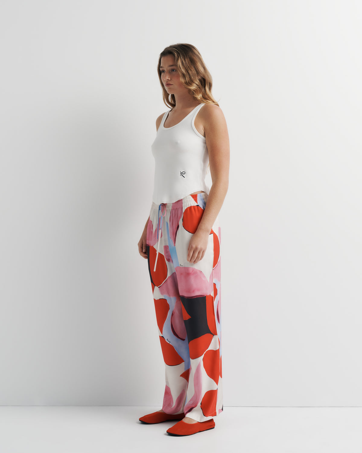 June Pant in pink, red and black abstract print, three-quarter view on model, second look.