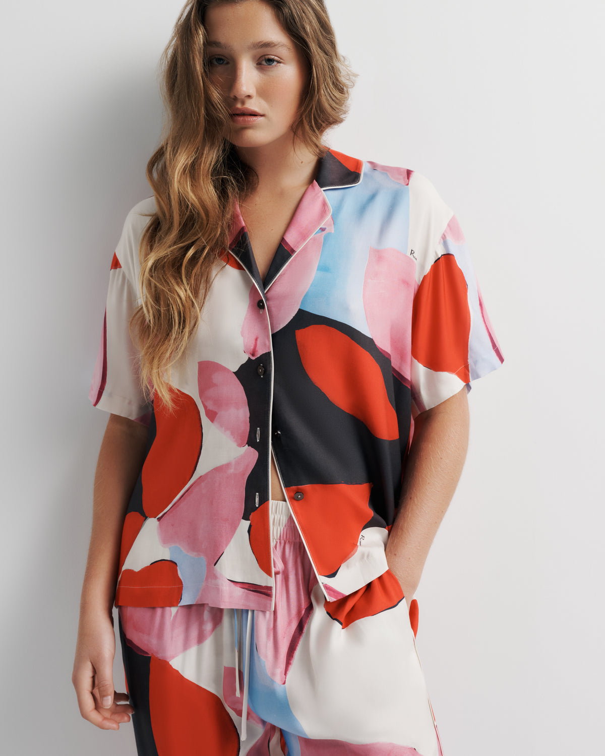 Reese Shirt in pink, red and black abstract print, front close-up on model.