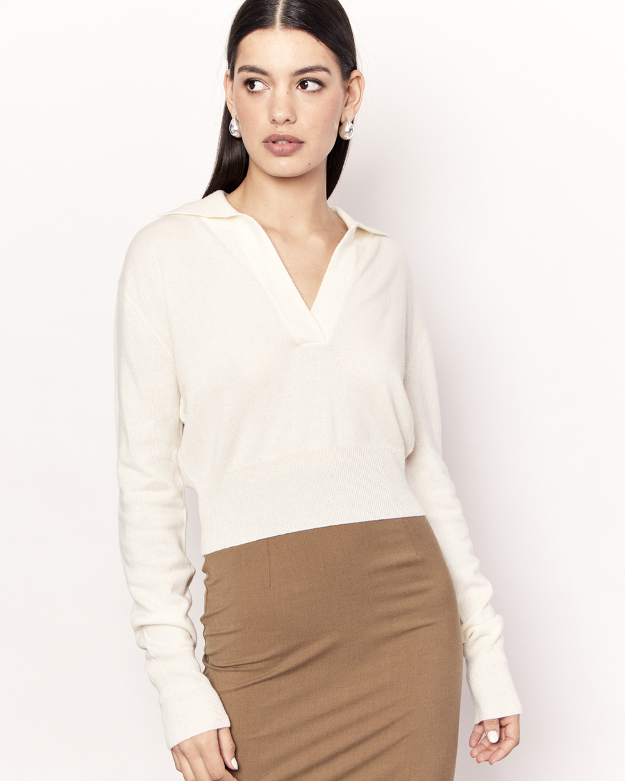 The Cropped Collared Sweater is a trans-seasonal knitwear essential, featuring a collar, deep-v neckline, and cropped hem. It is crafted from a luxurious Wool Cashmere blend in Cream. Now available at Romy. 