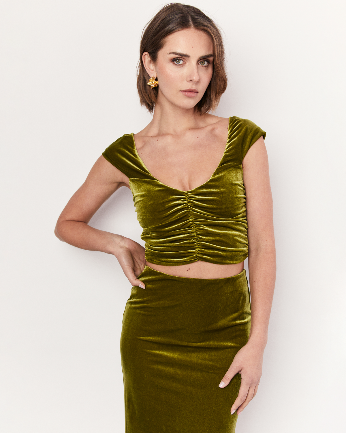 The Velvet Top exudes elegance and lust featuring ruched detailing, an off the shoulder neckline, and a cropped length. It is crafted from a plush stretch Velvet fabrication in a stunning green hue. Now available at Romy. 