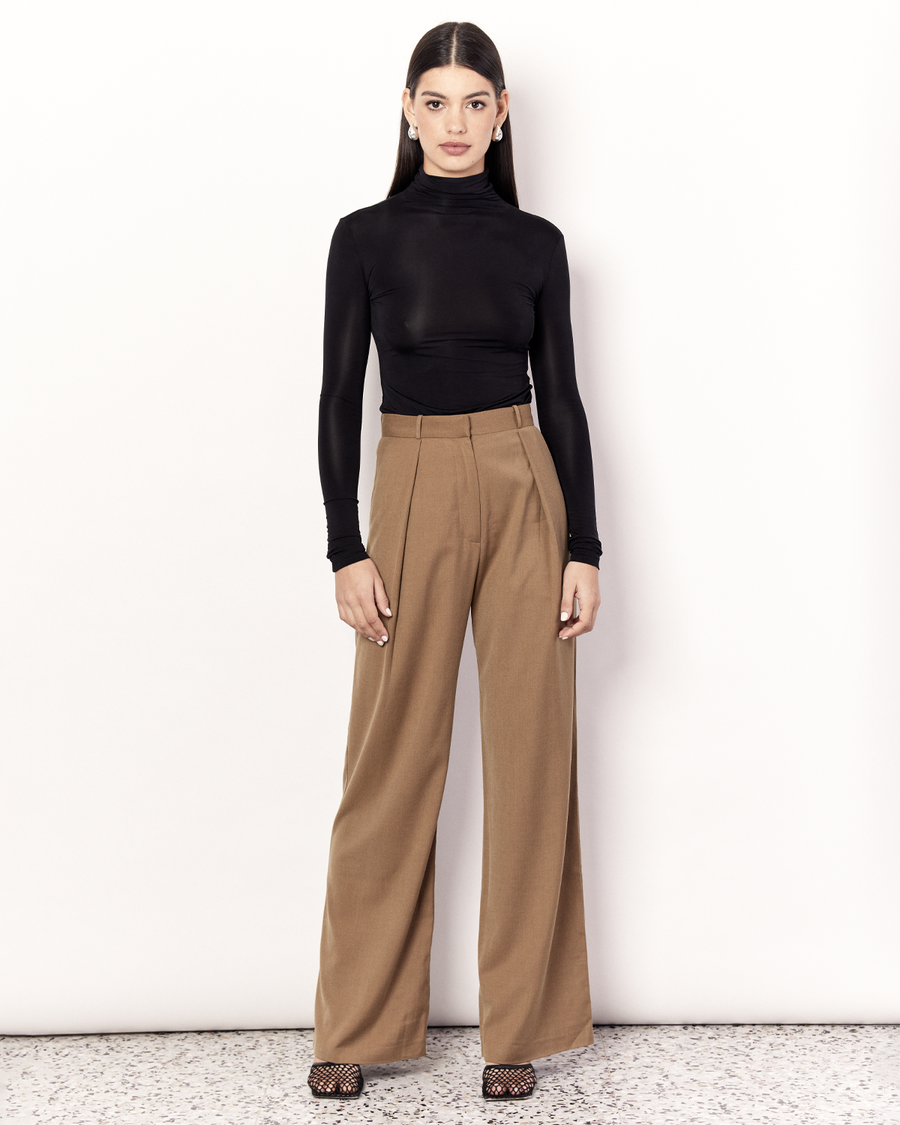 The Pleat Front Pant are an easy-wearing wide leg pant featuring a hidden clasp closure, pockets, and pleated detailing down the front, creating a subtle drape in the leg. They are crafted from a soft wool blend in Tan. Now available at Romy. 