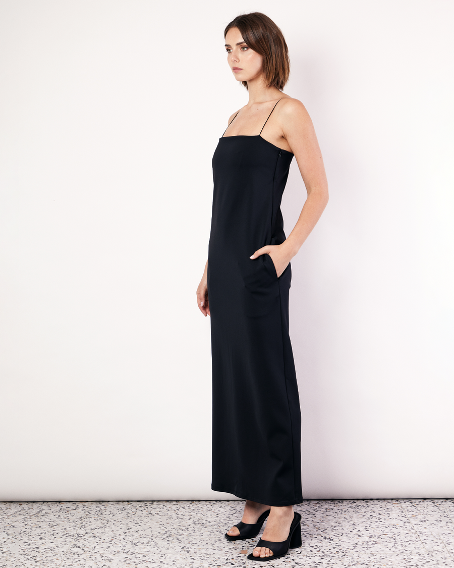 This floor-length bandeau dress is crafted from a luxurious stretch scuba fabrication, featuring rouleau shoulder straps and an inner shelf bra. With side pockets and a classic and elegant silhouette, this will soon become your go-to black dress. Now available at Romy. 
