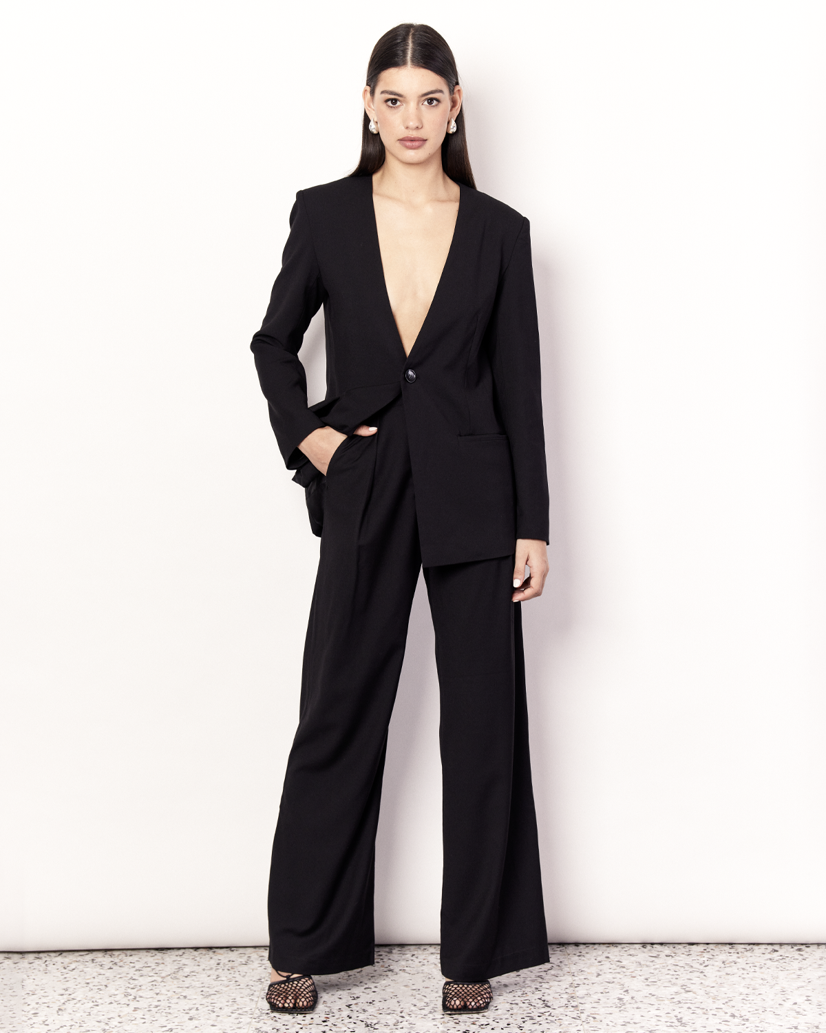 The Collarless Blazer is a versatile tailored silhouette featuring two front pockets, a button closure and a collarless neckline. It is fully lined and is crafted from a soft wool blend in Black. Now available at Romy. 