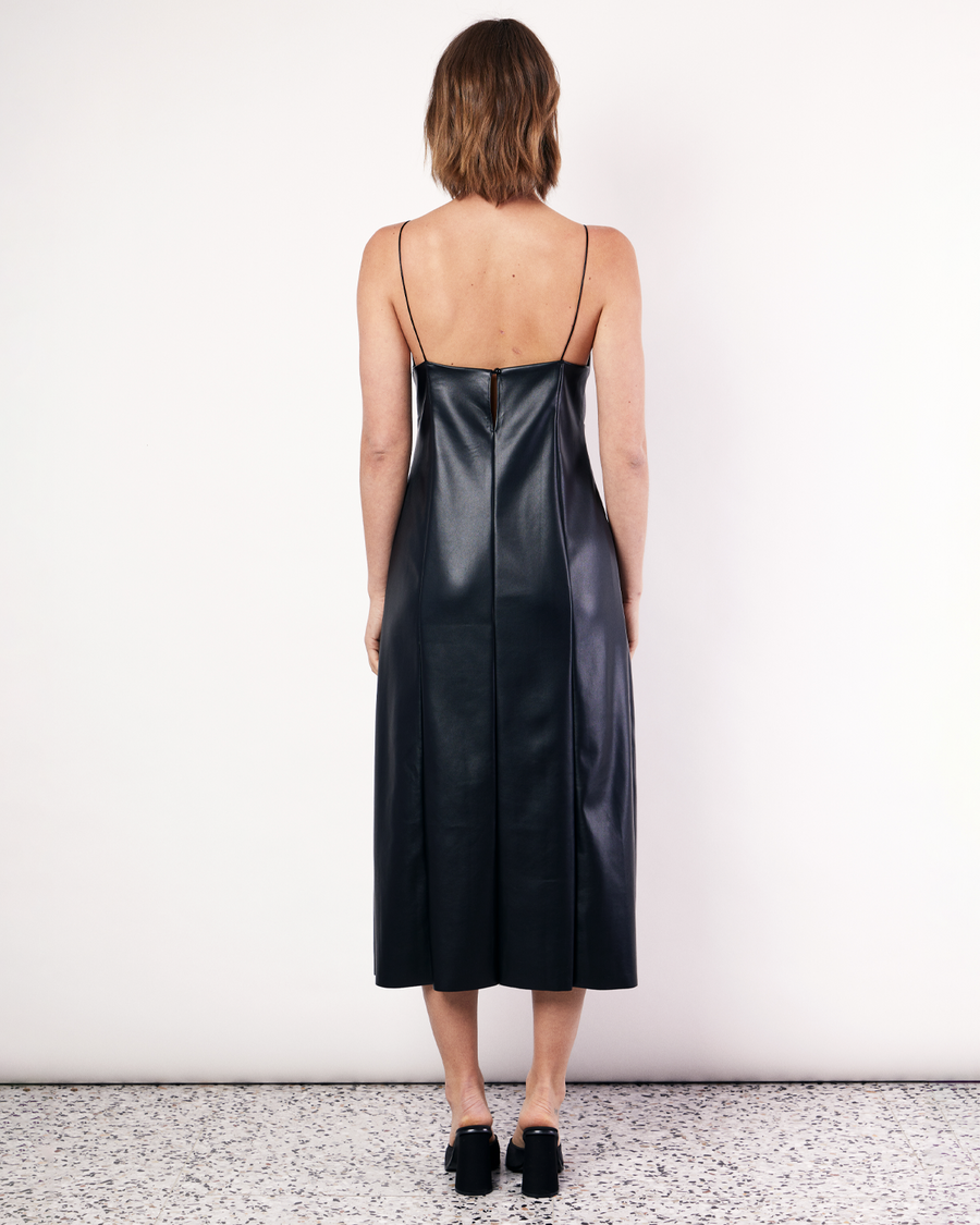 The Deep V Vegan Leather Midi Dress is a chic style featuring flattering front seam detailing and rouleau straps. It is crafted from a buttery soft Vegan leather fabrication in Black. Now available at Romy. 