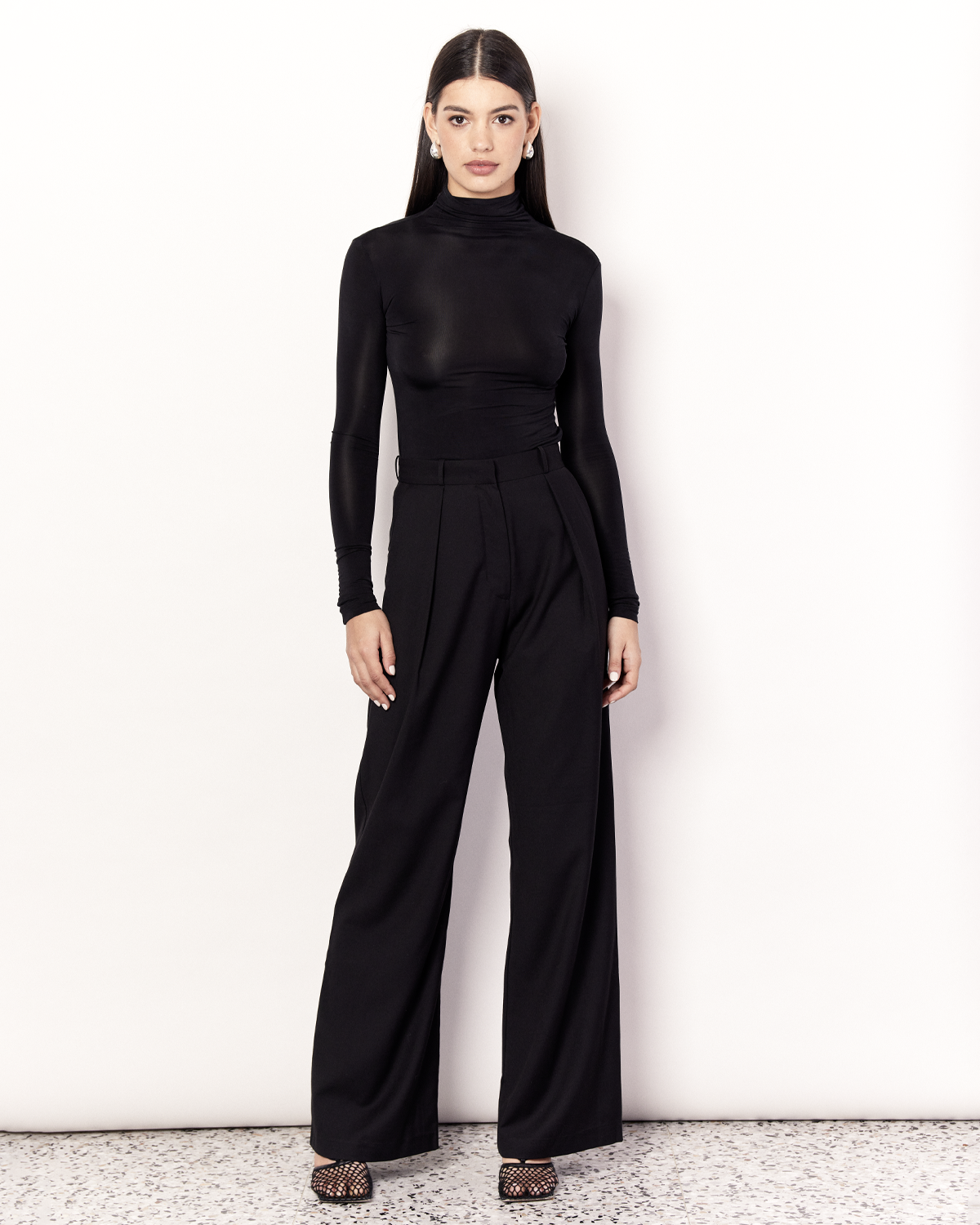 The Pleat Front Pant are an easy-wearing wide leg pant featuring a hidden clasp closure, pockets, and pleated detailing down the front, creating a subtle drape in the leg. They are crafted from a soft wool blend in Black. Now available at Romy. 