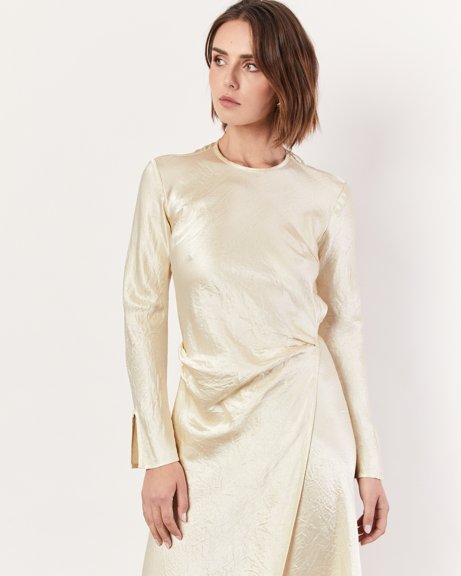 The Long Sleeve Wrap Dress boasts a fluid form and elevated style, featuring gathered detailing and a leg split. It is crafted from 100% Crushed Acetate in a Lemon hue. Now available at Romy. 