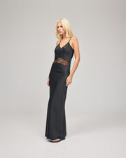 A black maxi dress features a delicate floral lace cut-out that accentuates the waist. It is bias-cut to effortlessly skim the body, creating a sleek and flattering silhouette. Show now.