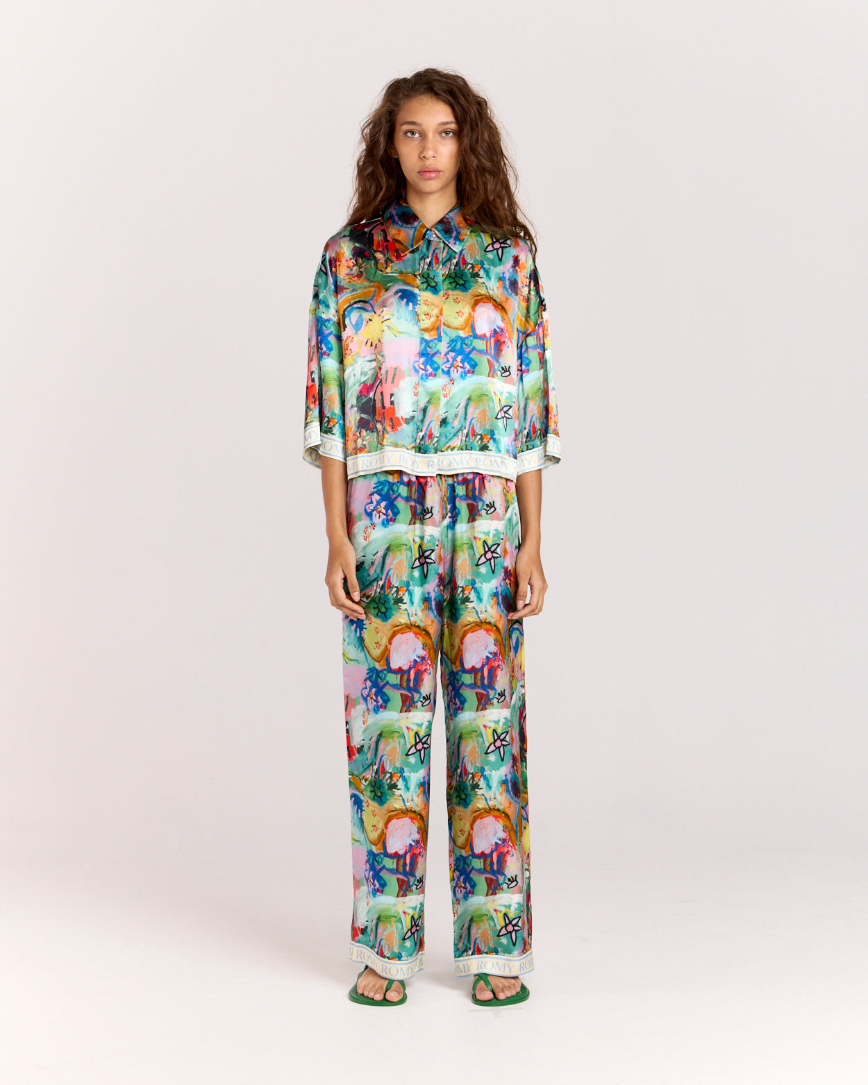 Discover the charm of our cropped oversized shirt, crafted from a matte twill blend of viscose and recycled rayon. Adorned with an eye-catching artist print by Jake Pedro and a contrasting Romy hem, this versatile piece can be worn open over a swimsuit, paired with a singlet, or styled with matching pants for a complete look.