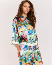 Discover the charm of our cropped oversized shirt, crafted from a matte twill blend of viscose and recycled rayon. Adorned with an eye-catching artist print by Jake Pedro and a contrasting Romy hem, this versatile piece can be worn open over a swimsuit, paired with a singlet, or styled with matching pants for a complete look.