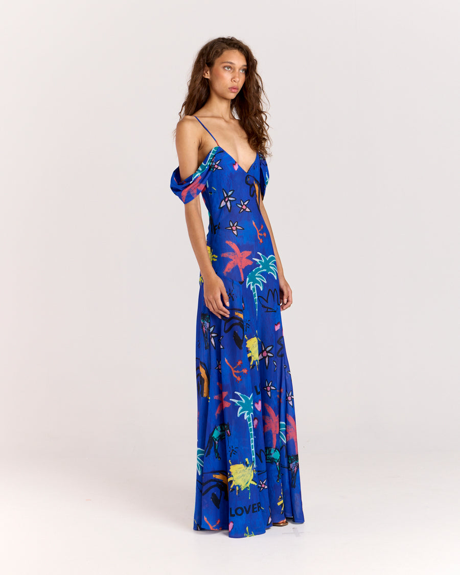 Make a bold statement with the Lover Gown, featuring Jake Pedro's exclusive Lover Print in a striking blue hue. Designed with a drop waist, adjustable straps, and a voluminous floor-length skirt, this gown offers elegance with a touch of sheerness.