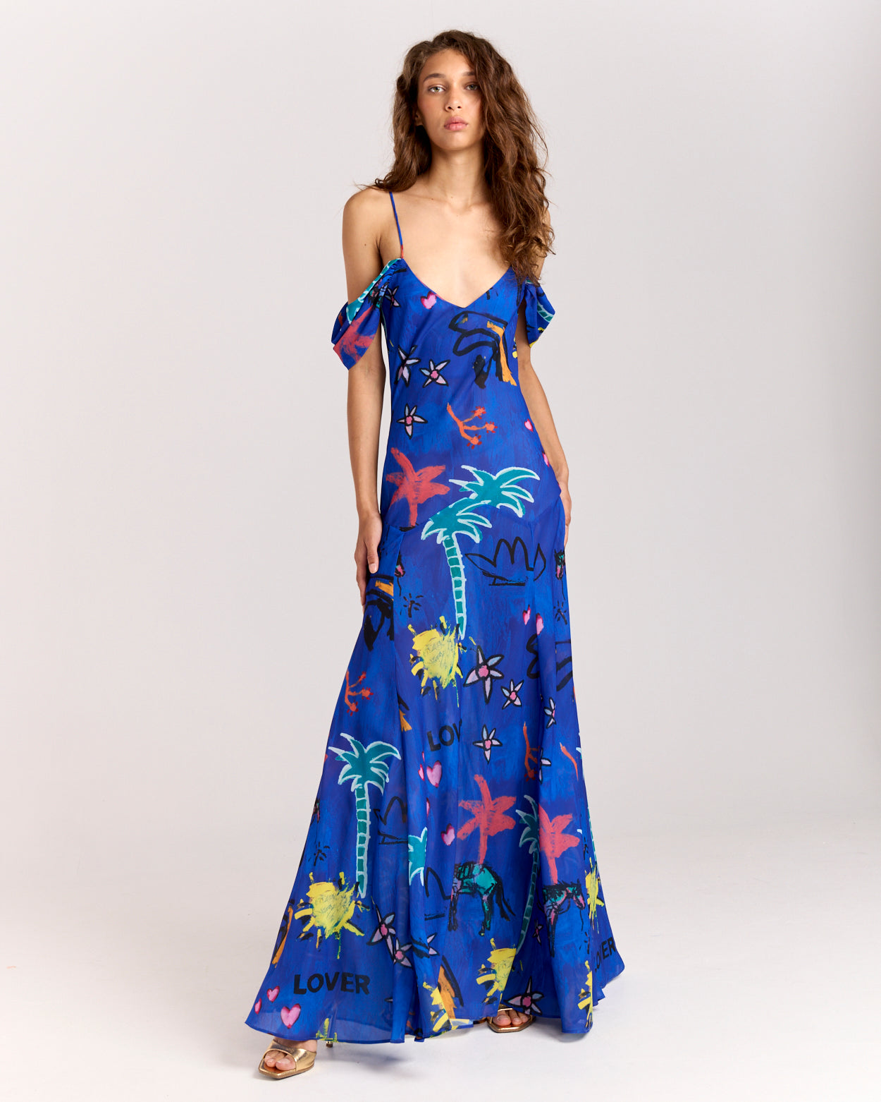 Make a bold statement with the Lover Gown, featuring Jake Pedro's exclusive Lover Print in a striking blue hue. Designed with a drop waist, adjustable straps, and a voluminous floor-length skirt, this gown offers elegance with a touch of sheerness.